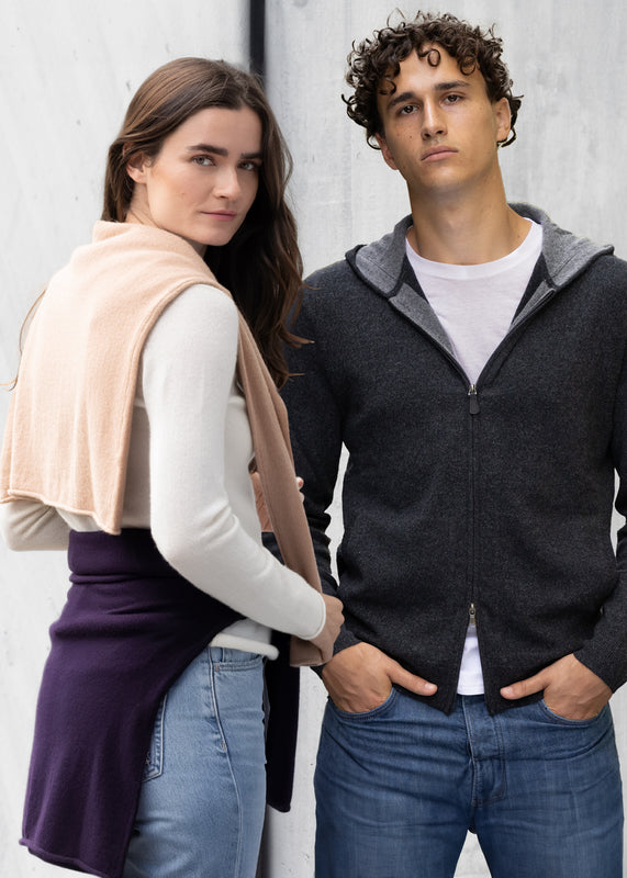 Two people wearing casual cashmere sweaters against a plain background