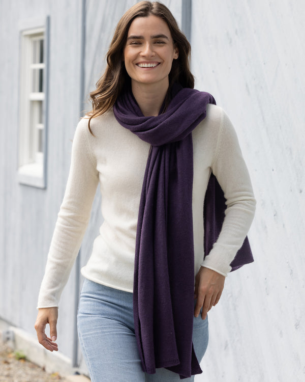 Woman walking in front of a barn wearing cashmere crew neck and Kennedy Travel wrap in Currant