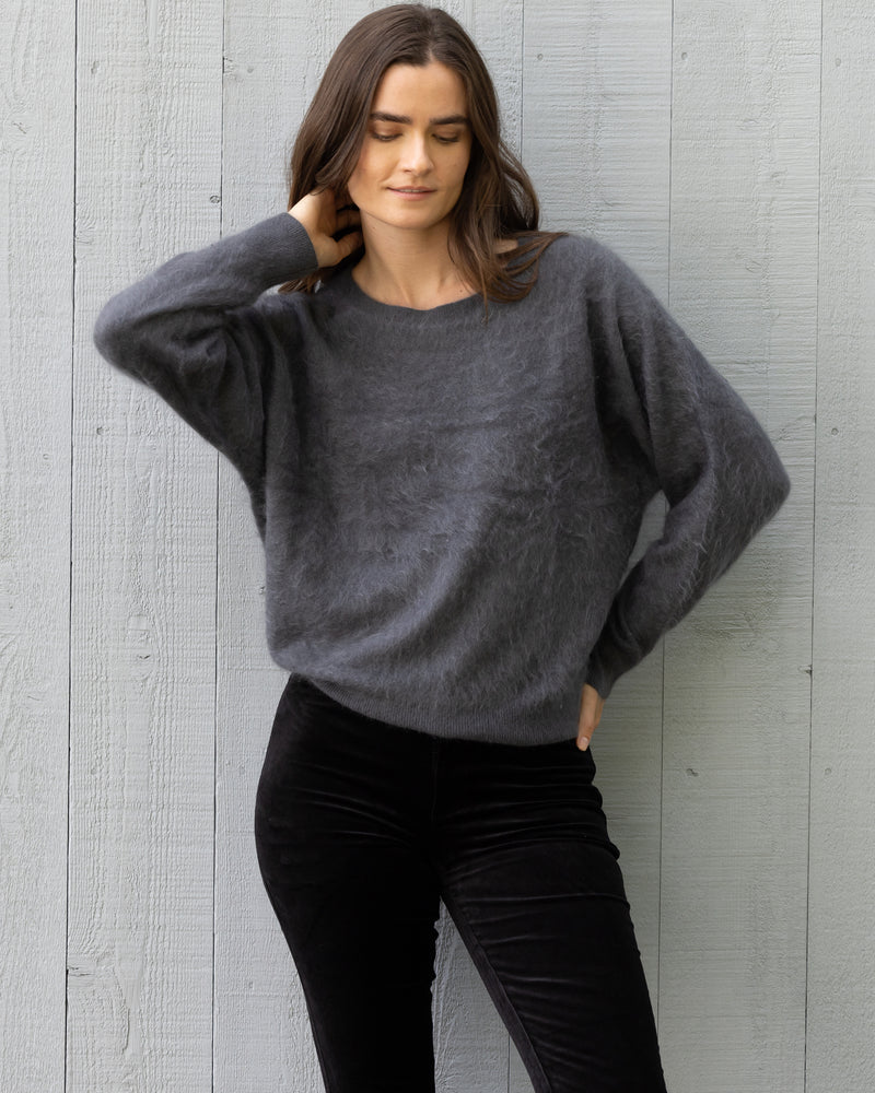 Woman wearing Sedgwick Sweater in Asphalt against barn door