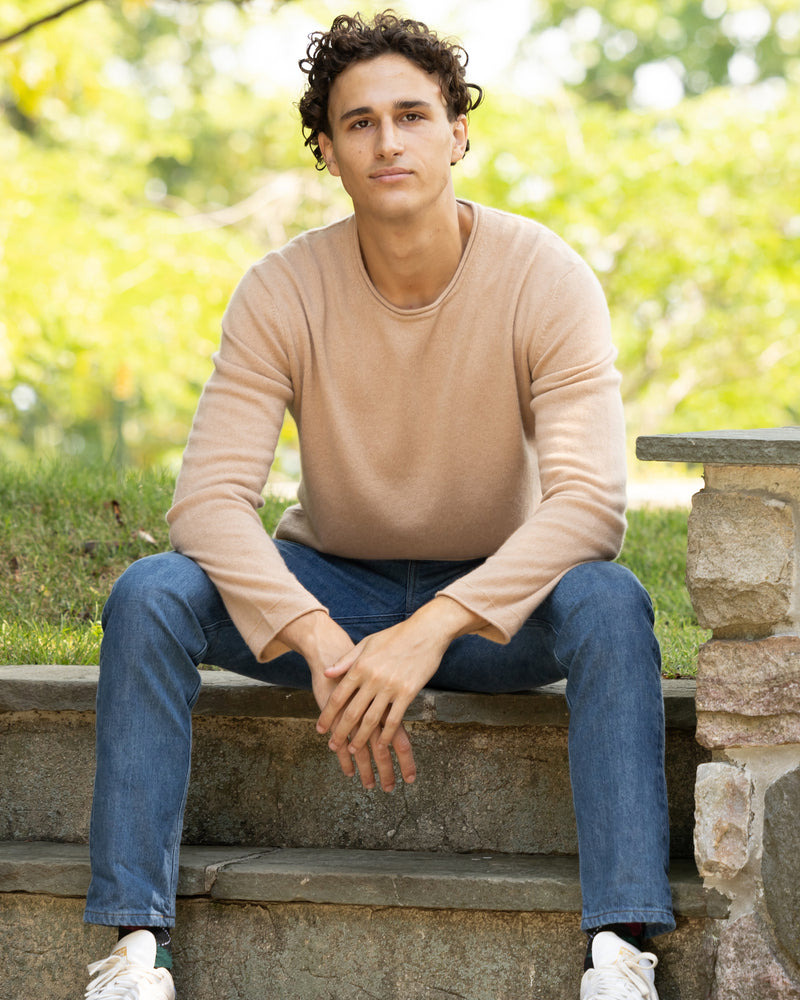 Man sitting on steps and wearing Nomad Sweater in Camel